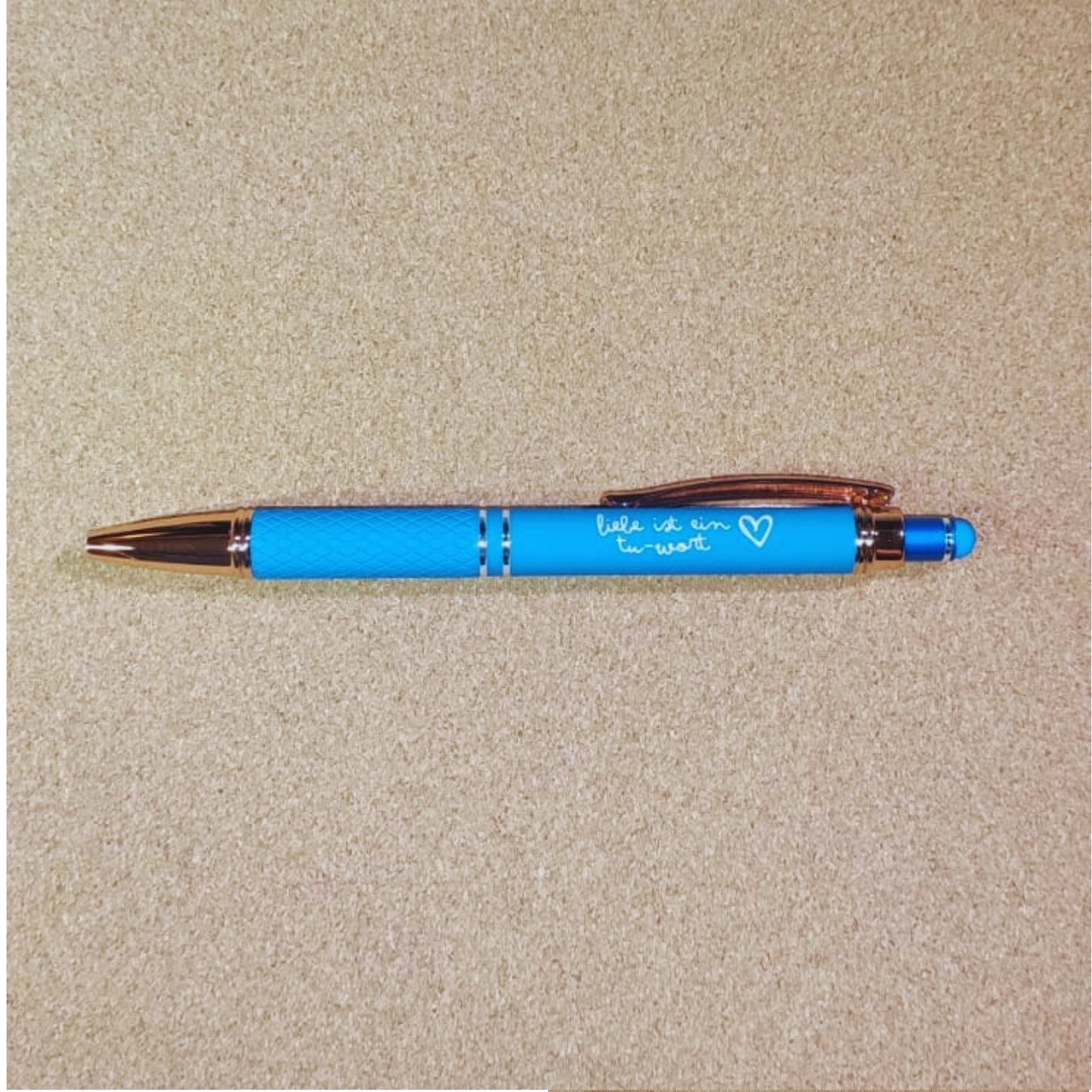 Kugelschreiber "Liebe ist ein Tu-Wort" in Hellblau mit Rosegold-Akzenten, diamantgemustertem Griff und Soft Touch Finish. Perfekt als eleganter Begleiter für den Alltag.