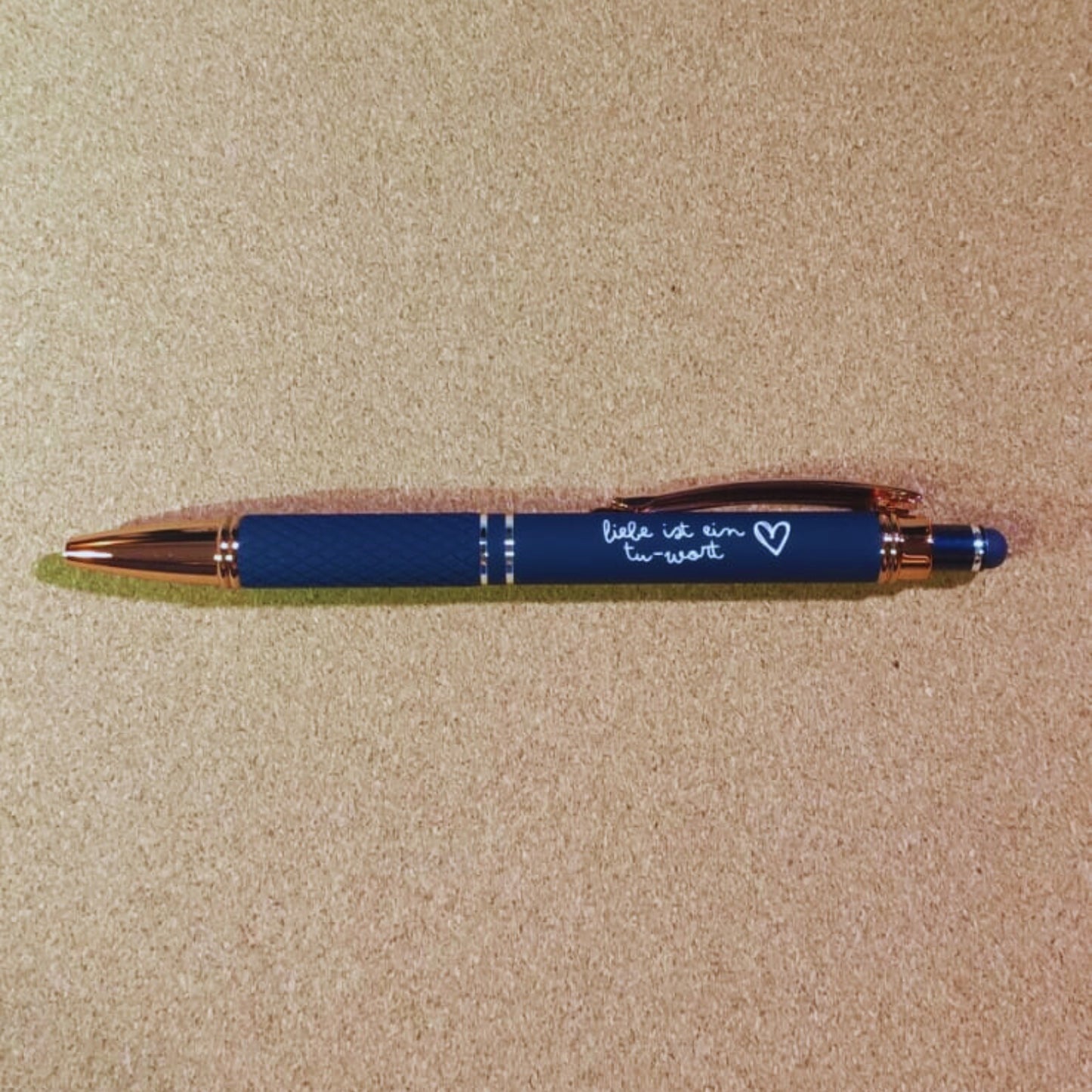 Kugelschreiber "Liebe ist ein Tu-Wort" in Marineblau mit Rosegold-Akzenten, diamantgemustertem Griff und Soft Touch Finish. Stilvoll und funktional.