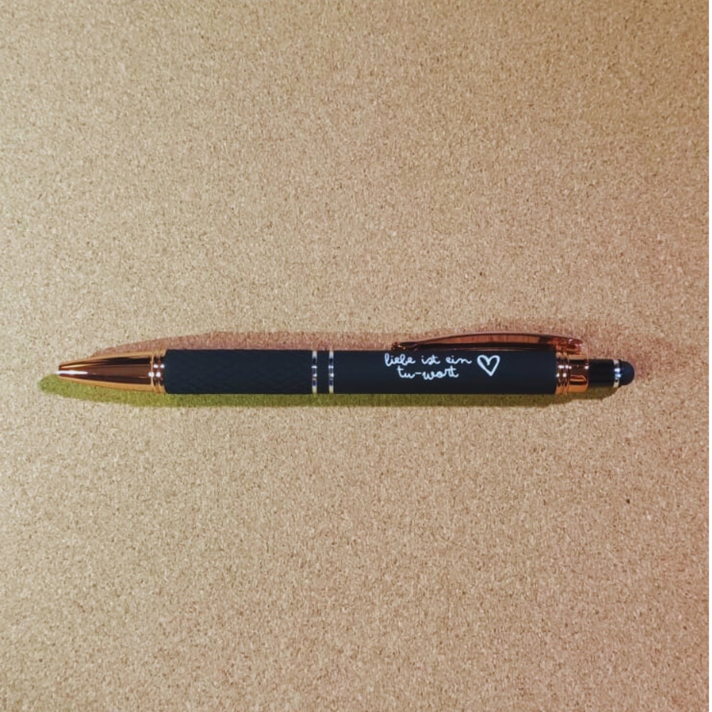 Kugelschreiber "Liebe ist ein Tu-Wort" in Schwarz mit Rosegold-Akzenten, diamantgemustertem Griff und Soft Touch Finish. Perfekt für stilvolle Notizen und besondere Momente.