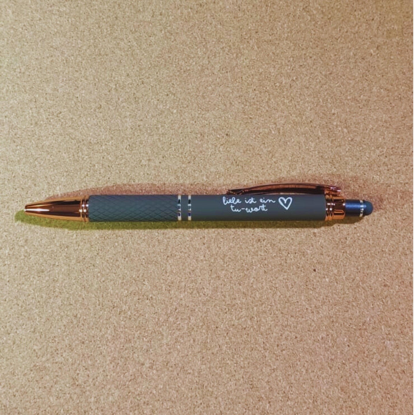 Kugelschreiber "Liebe ist ein Tu-Wort" in Taupe mit Rosegold-Akzenten, diamantgemustertem Griff und Soft Touch Finish. Ideal als durchdachtes Geschenk.