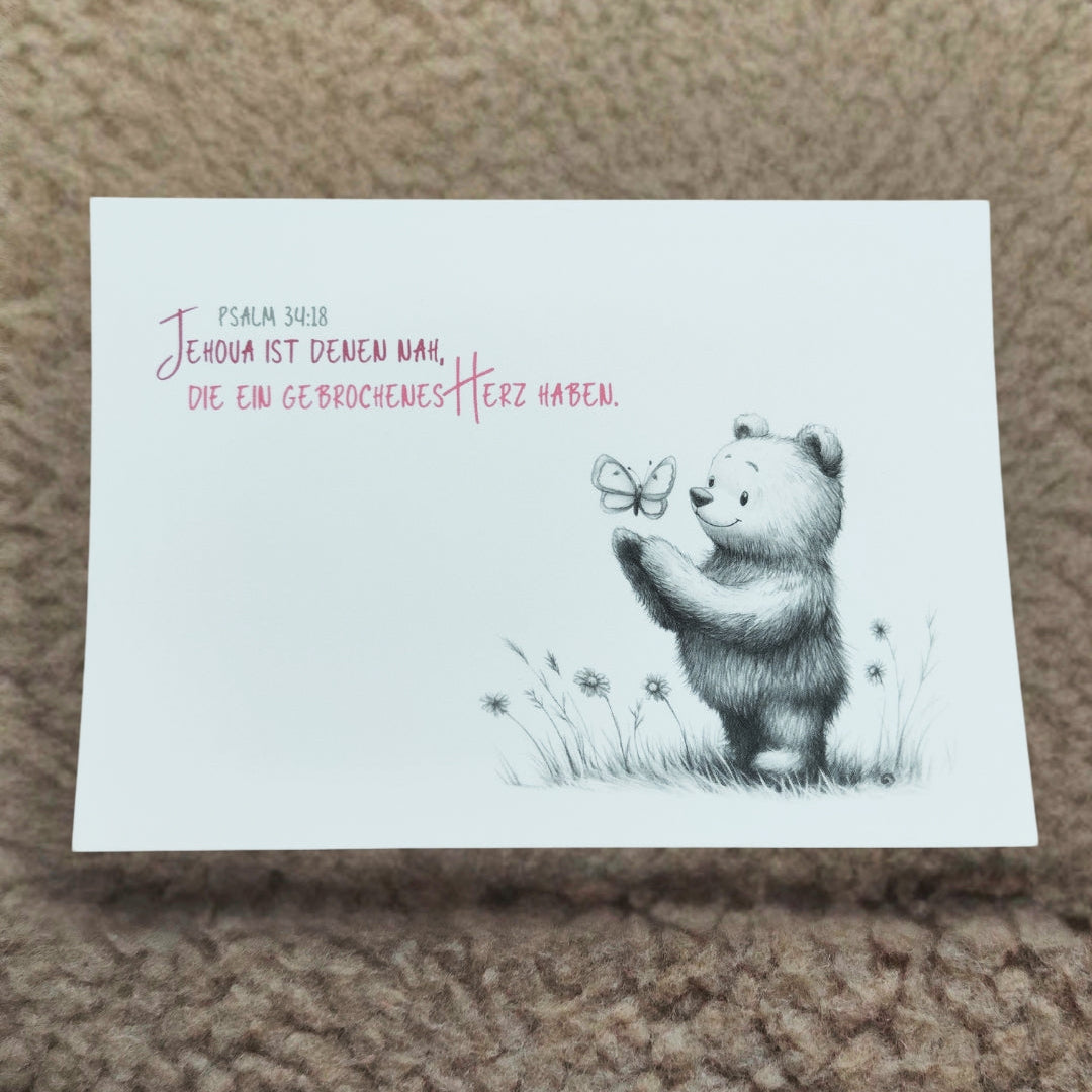 Postkarte "Sanfter Trost" mit detailreicher Bleistiftzeichnung: ein freundlicher Bär hält sanft einen Schmetterling. Inspiriert von Psalm 34:18: „Jehova ist nahe denen, die ein gebrochenes Herz haben.“ Ideal als Trostspender oder liebevolle Geste.