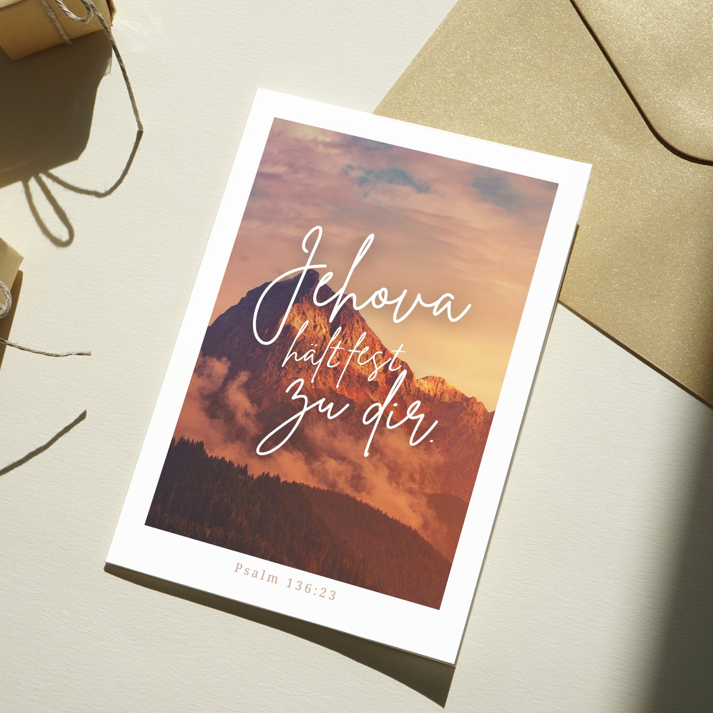 Postkarte mit dem Motiv eines Berges bei Sonnenaufgang und der ermutigenden Botschaft "Jehova hält fest zu dir", inspiriert von Psalm 136:23. Die Karte vermittelt Trost, Hoffnung und Glaubensstärkung und eignet sich ideal als liebevolle Geste für besondere Menschen.