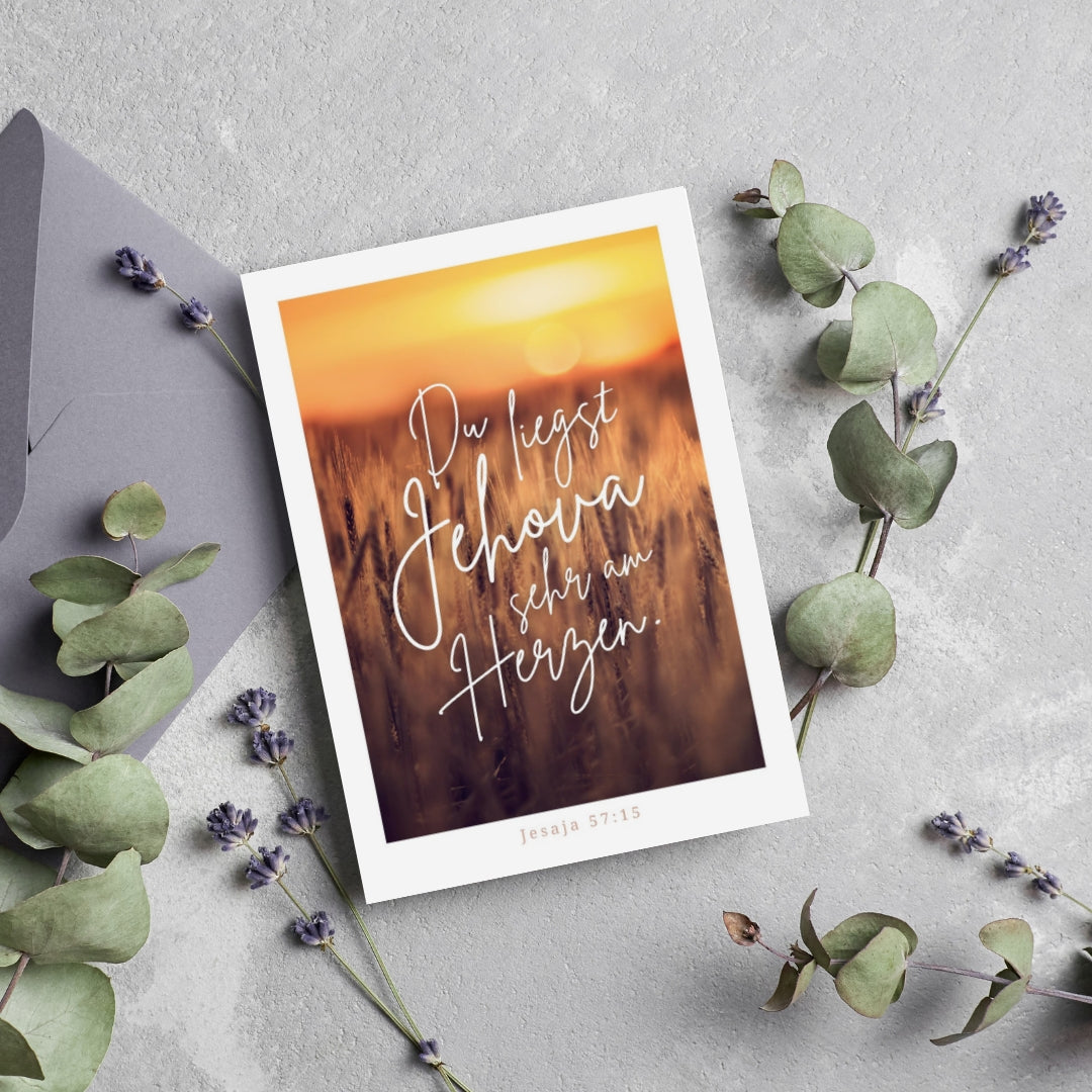 Postkarte "Am Herzen" mit Motiv eines goldenen Weizenfelds im Sonnenaufgang, inspiriert von Jesaja 57:15. Ideal als Ermutigung oder Zeichen der Wertschätzung für Glaubensgeschwister.