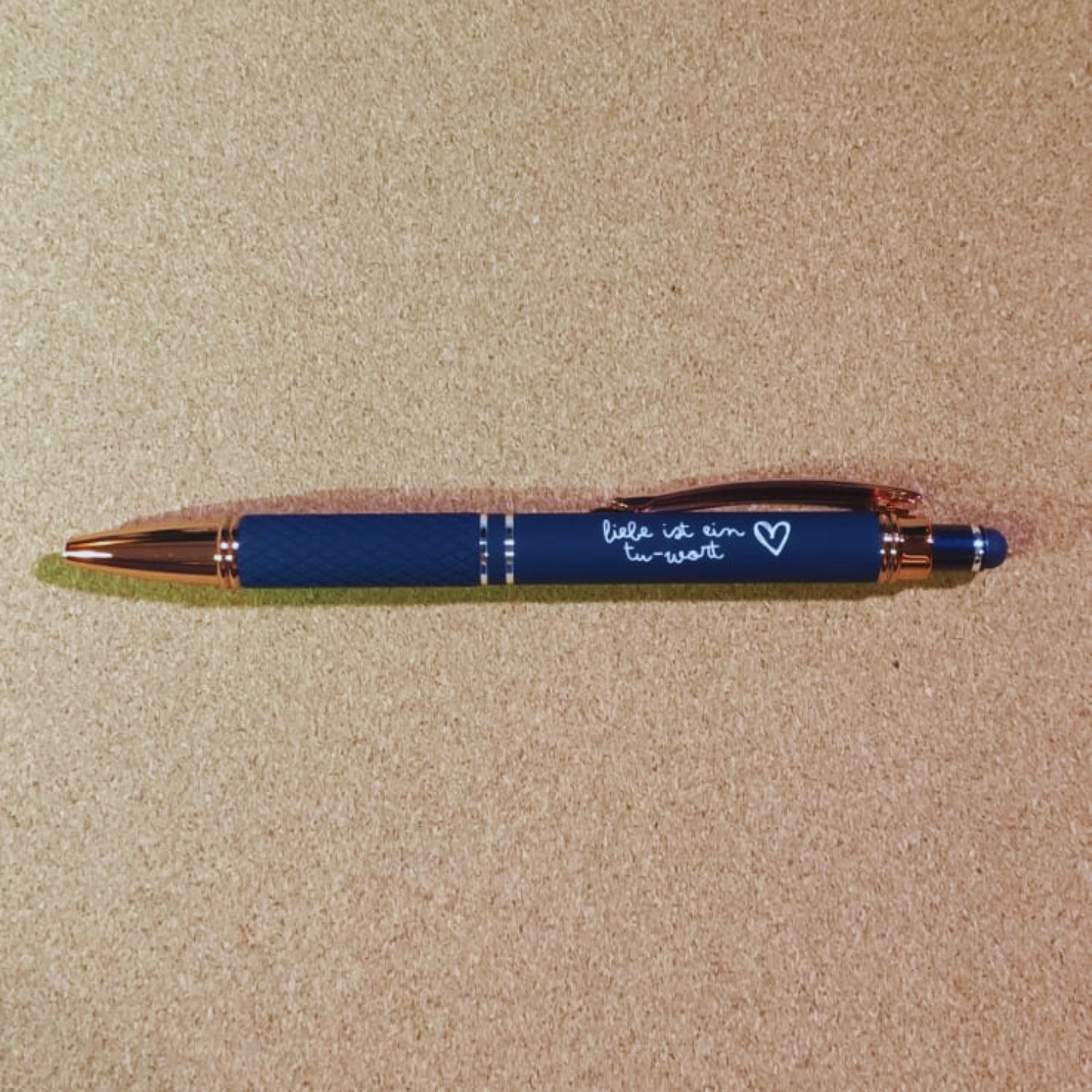 Kugelschreiber "Liebe ist ein Tu-Wort" in Marineblau mit Rosegold-Akzenten, diamantgemustertem Griff und Soft Touch Finish. Stilvoll und funktional.